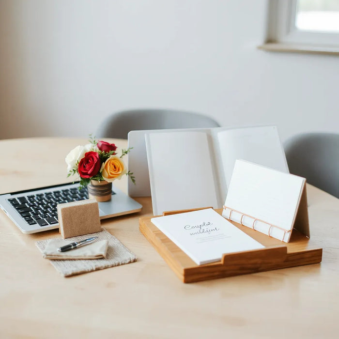 Wedding planner reviewing a timeline with a laptop, checklist folder, and neutral wedding stationery on a table